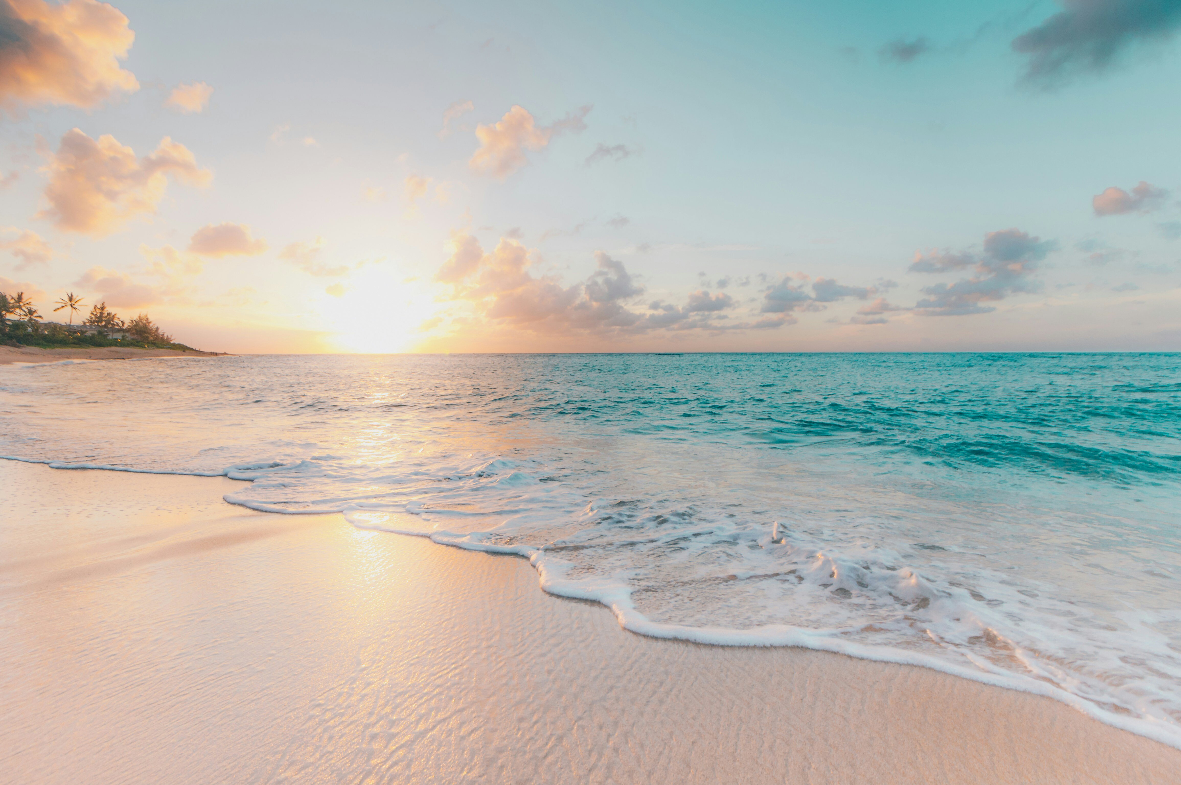 tropical beach scene, crystal and teal blue waves rolling into the white sane beach ats sunset